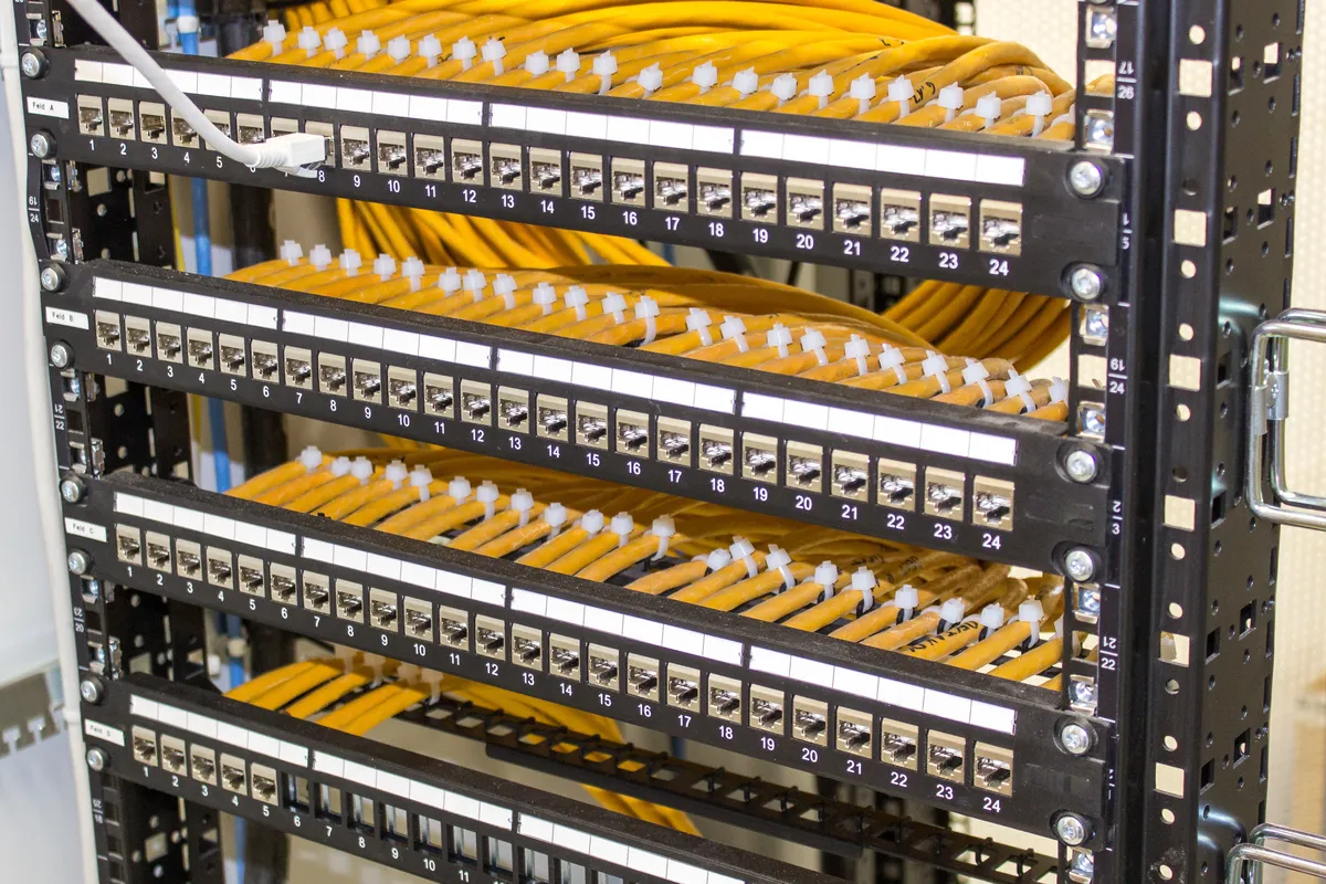 Combed yellow network cabling running into shielded patch panels in a rack